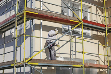 Maler beim Fassadenanstrich eines neuen Wohnhauses