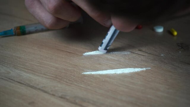 addict sniffs cocaine track with rolled bill