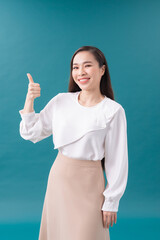 Smiling pretty young woman showing thumb up isolated on the blue background