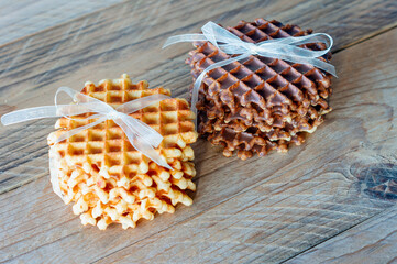 Two piles of delicious belgian waffles with honey and chocolate on wooden table.