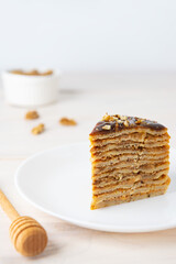 Slice of pancake cake with chocolate caramel and walnuts on a white plate. Maslenitsa or Shrovetide.