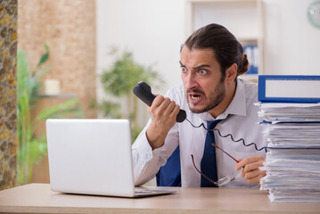 Young businessman unhappy with excessive work in the office