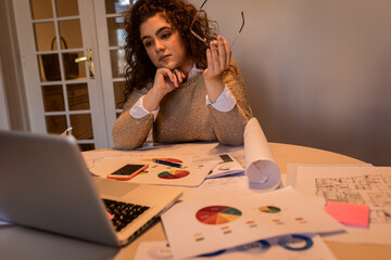 Young woman working at home using laptop in her living room.