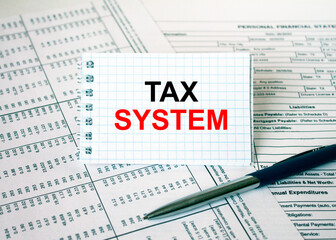 Obraz premium Notepad with text Tax System lying on financial tables with a pen