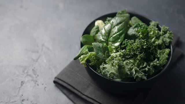 The camera pans along a salad leaf dish in a black plate, a dark napkin and a black background. Place for text