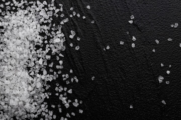 Coarse sea salt on black background, top view