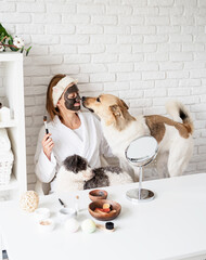 Young caucasian woman wearing bathrobes doing spa procedures with her dog