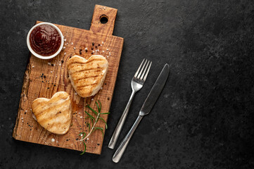 Obraz na płótnie Canvas Grilled chicken breast in the shape of a heart on a stone background with copy space.