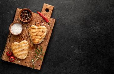 Obraz na płótnie Canvas Grilled chicken breast in the shape of a heart on a stone background with copy space.