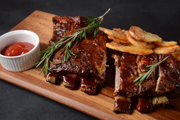 Closeup of pork ribs grilled with BBQ sauce and caramelized in honey. Tasty snack to beer on a wooden Board. Grilled pork ribs with spices on a stone background