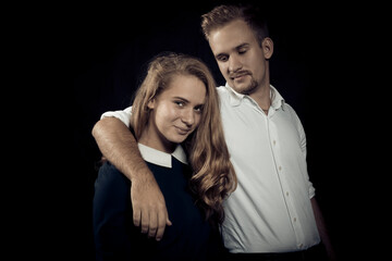 Young beautiful couple studio portrait on black background.
