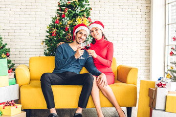Romantic sweet couple in santa hats having fun and drinking wine glasses while celebrating new year eve and enjoying spending time together in christmas time at home