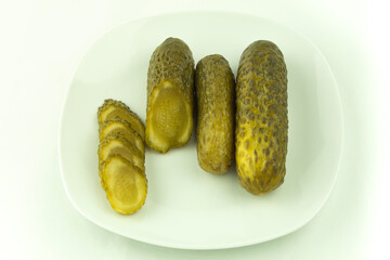 Pickled cucumbers whole and cut into rings on a light background top view