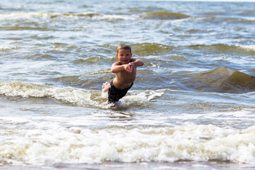 Young cheerful boy having fun at sea waves.