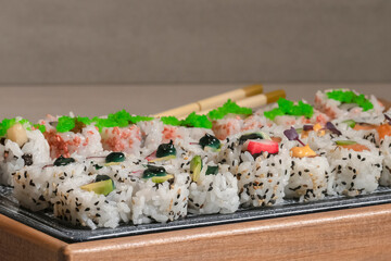 close up of delicious looking uramaki with out of focus chopsticks. Sushi and healthy food concept.