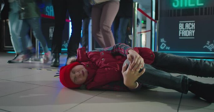 Injured child lying on floor with crowd running into mall