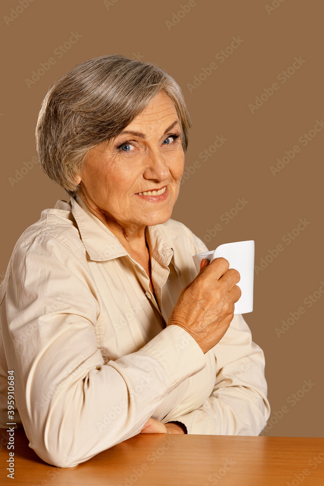 Poster portrait of beautiful smiling senior woman drinking tea