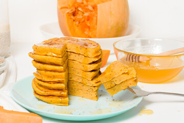 a stack of autumn pumpkin pancakes with Chia seeds and honey on a light background. delicious healthy vegetarian diet Breakfast. the concept of taking care of your body, the keto diet .