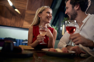 young couple looking each other, smiling, laughing,  having romantic dinner in a restaurant.