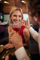 young man with a beard cuddling hair of a beautiful attractive blonde at romantic dinner in restaurant