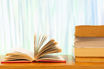 A pile of books and open book with blurred colour as background and copy space