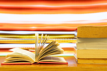 A pile of books and open book with blurred colour as background and copy space