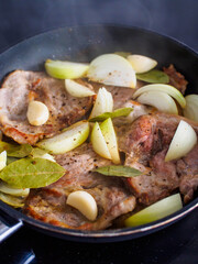 Pork steaks in frying pan with onion
