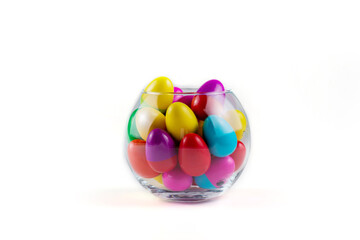 Colorful Plastic Easter Eggs in a glass vase on white background