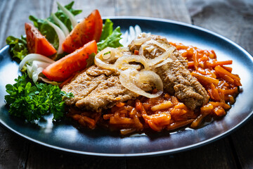 Fish dish - fried fish fillet on vegetable sauce on wooden table
