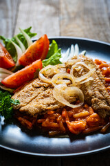 Fish dish - fried fish fillet on vegetable sauce on wooden table
