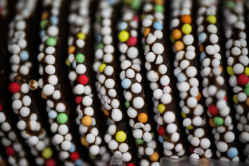 Macro close up of chocolate cookies surface with colorful sugar pearls (focus on center)