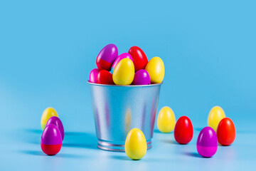 Colorful Plastic Easter Eggs in a metal bucket on blue background