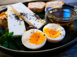 Soft boiled eggs with Greek salad served on wooden table 