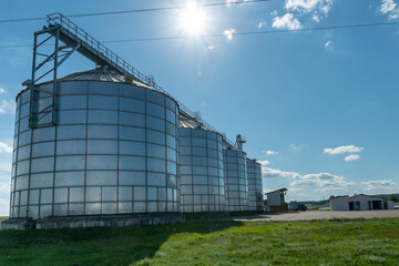 silver silos on agro manufacturing plant for processing drying cleaning and storage of agricultural products, flour, cereals and grain. Large iron barrels of grain. Granary elevator