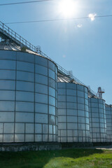 silver silos on agro manufacturing plant for processing drying cleaning and storage of agricultural products, flour, cereals and grain. Large iron barrels of grain. Granary elevator