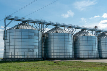 silver silos on agro manufacturing plant for processing drying cleaning and storage of agricultural products, flour, cereals and grain. Large iron barrels of grain. Granary elevator