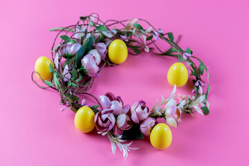 Obraz premium Colored Easter wreath and plastic eggs on a pink background