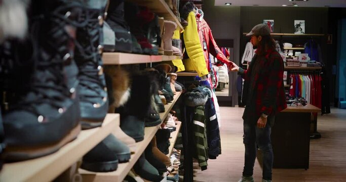 Man goes shopping during winter vacation. We can see winter clothes, perfect to go skiing in the mountains 4K