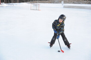 Fototapeta na wymiar A young ice hockey amateur player on ice rink playing hockey with a stick in winter in Sweden
