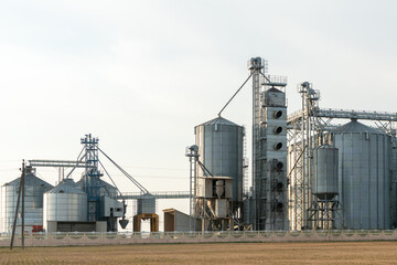 Obraz premium silver silos on agro manufacturing plant for processing drying cleaning and storage of agricultural products, flour, cereals and grain. Large iron barrels of grain. Granary elevator