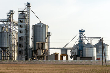 silver silos on agro manufacturing plant for processing drying cleaning and storage of agricultural products, flour, cereals and grain. Large iron barrels of grain. Granary elevator
