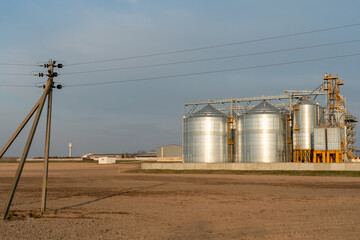 Obraz premium silver silos on agro manufacturing plant for processing drying cleaning and storage of agricultural products, flour, cereals and grain. Large iron barrels of grain. Granary elevator