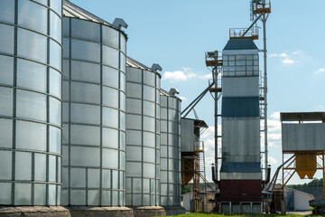 silver silos on agro manufacturing plant for processing drying cleaning and storage of agricultural products, flour, cereals and grain. Large iron barrels of grain. Granary elevator