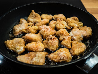 Chicken breast nuggets frying in pan
