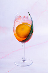 Aperol spritz cocktail on a pink background.