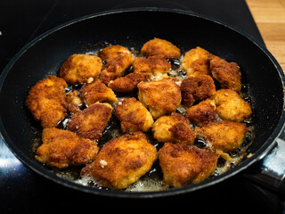 Chicken breast nuggets frying in pan
