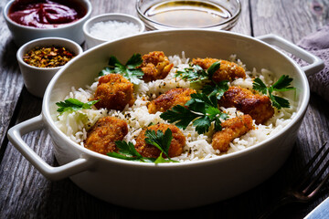 Chicken nuggets with rice and vegetables on wooden table
