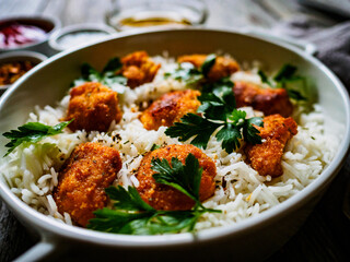 Chicken nuggets with rice and vegetables on wooden table
