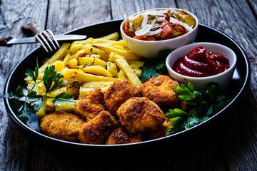 Fried breadcrumb chicken nuggets with French fries and vegetables
