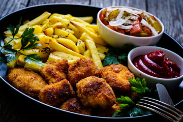 Fried breadcrumb chicken nuggets with French fries and vegetables
